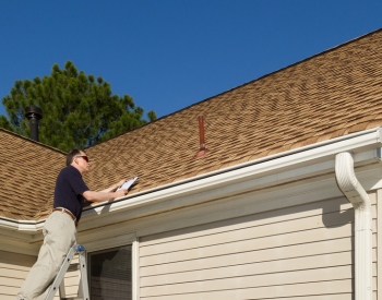 Roofer inspecting a roof in Moore during summer